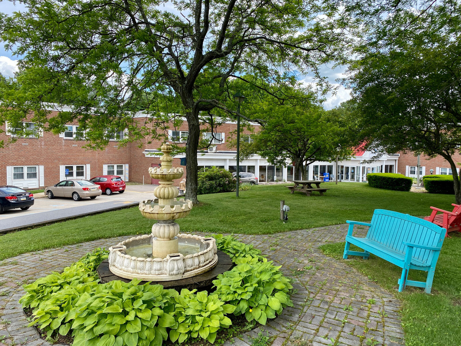 Park area with fountain, greenery, and colorful seating.