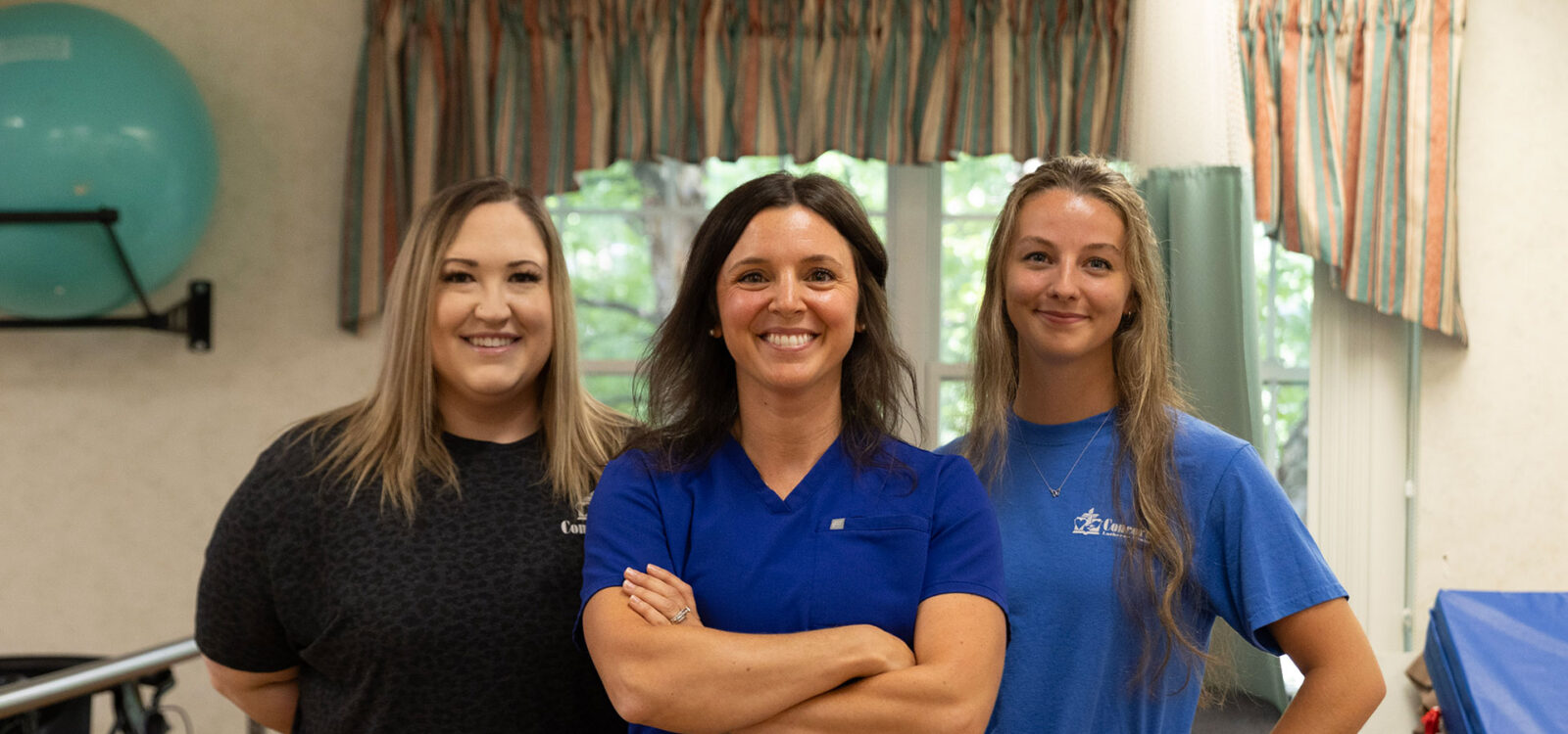 Three female professionals posing in a healthcare setting.