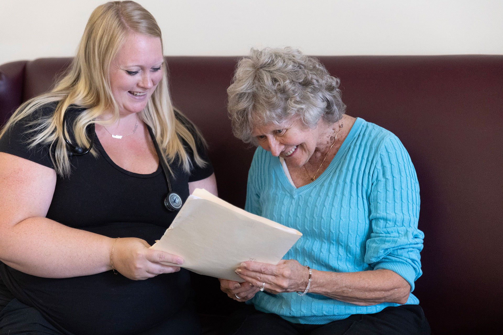 Two women sharing a joyful moment while reading together.
