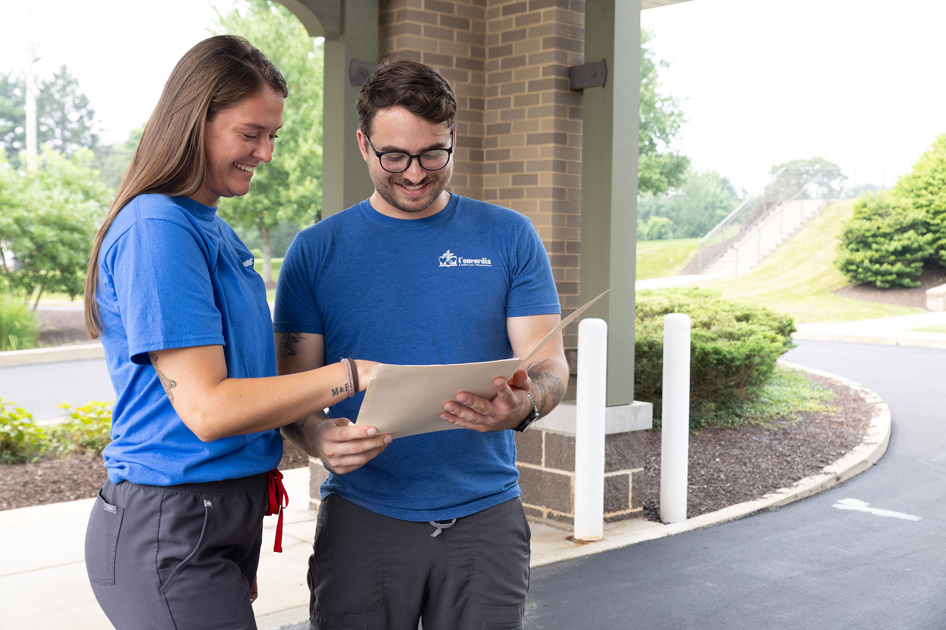 Two people reviewing documents outdoors, smiling and engaged.