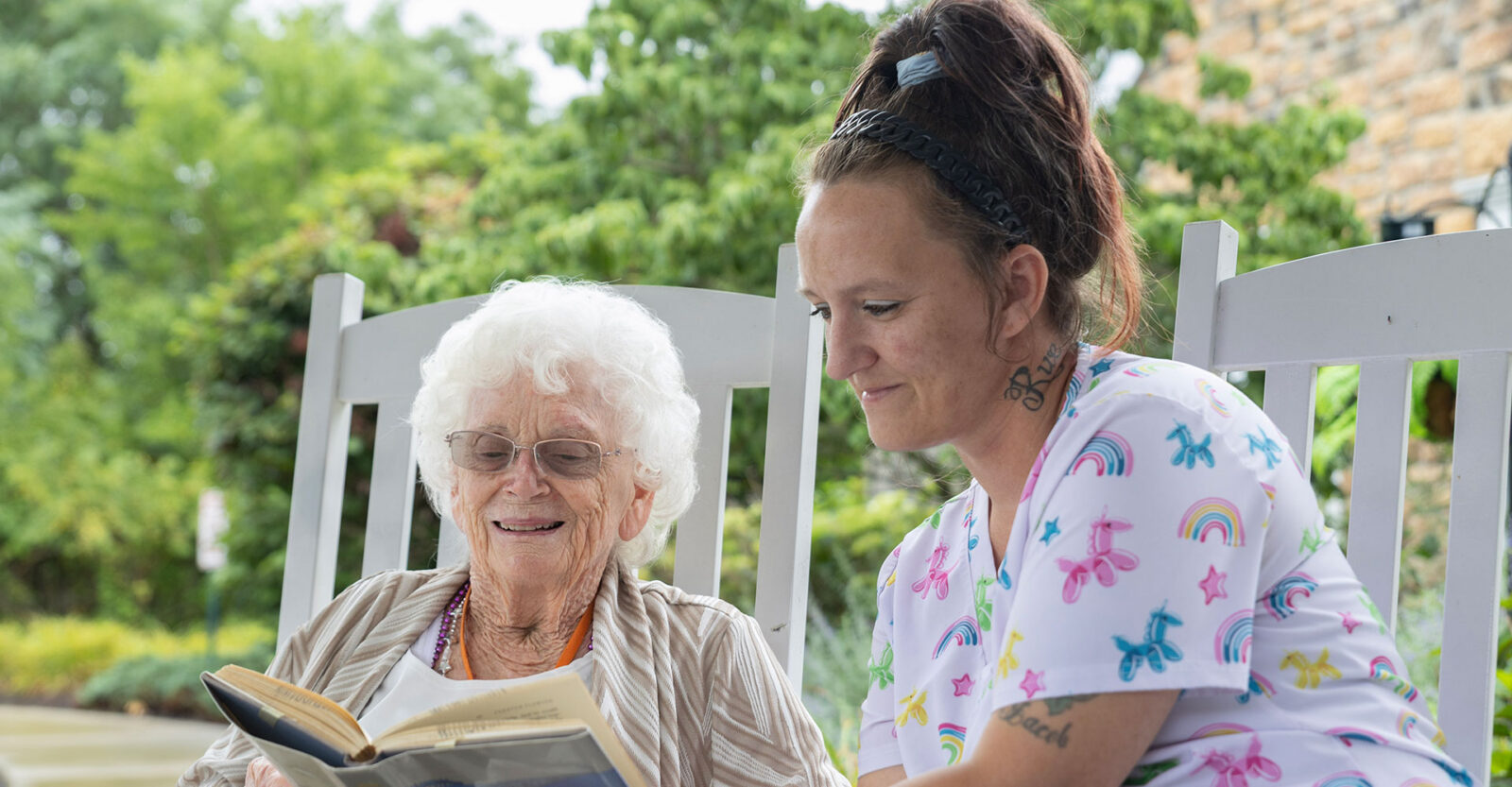 Smiling women enjoy reading together on a porch.