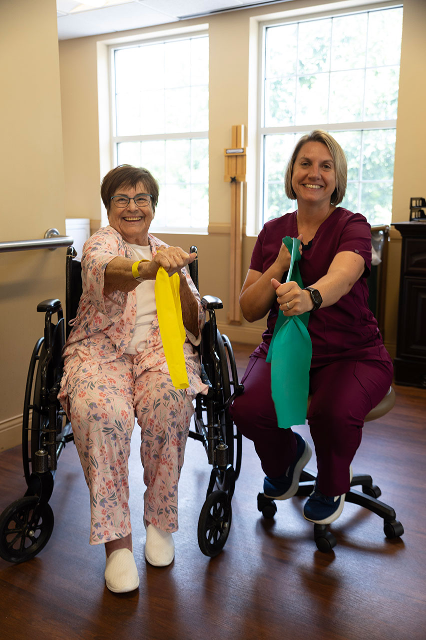 Two women using resistance bands during therapy session.