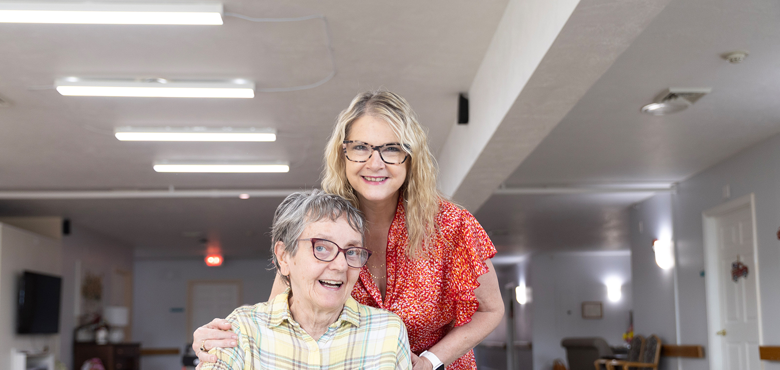 Smiling women in a bright indoor setting, sharing a moment.