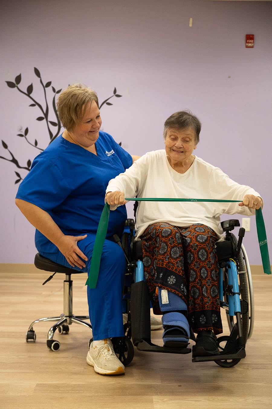 Caregiver assists a senior woman with therapy exercises.