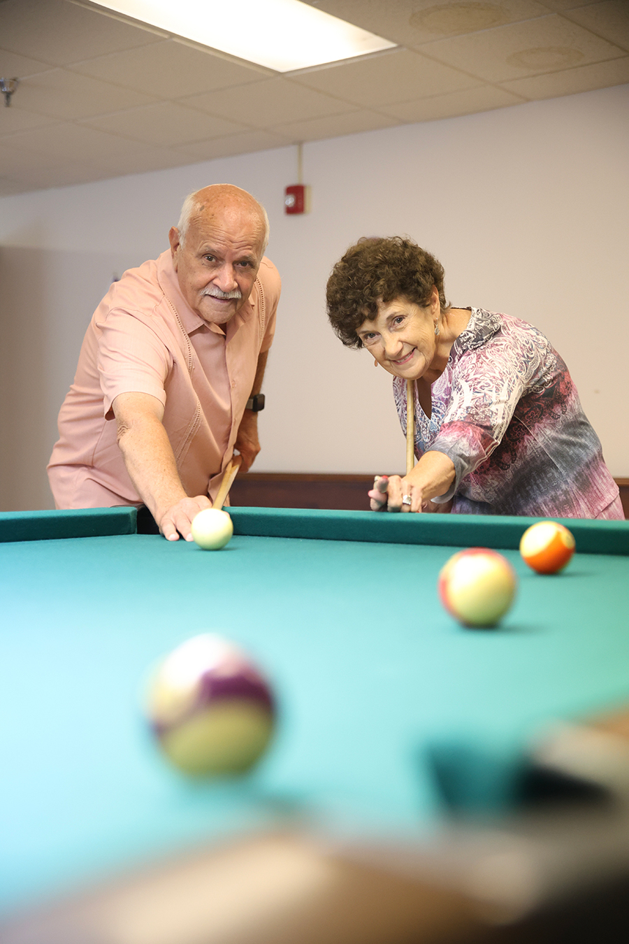 Two seniors enjoying a game of billiards together.