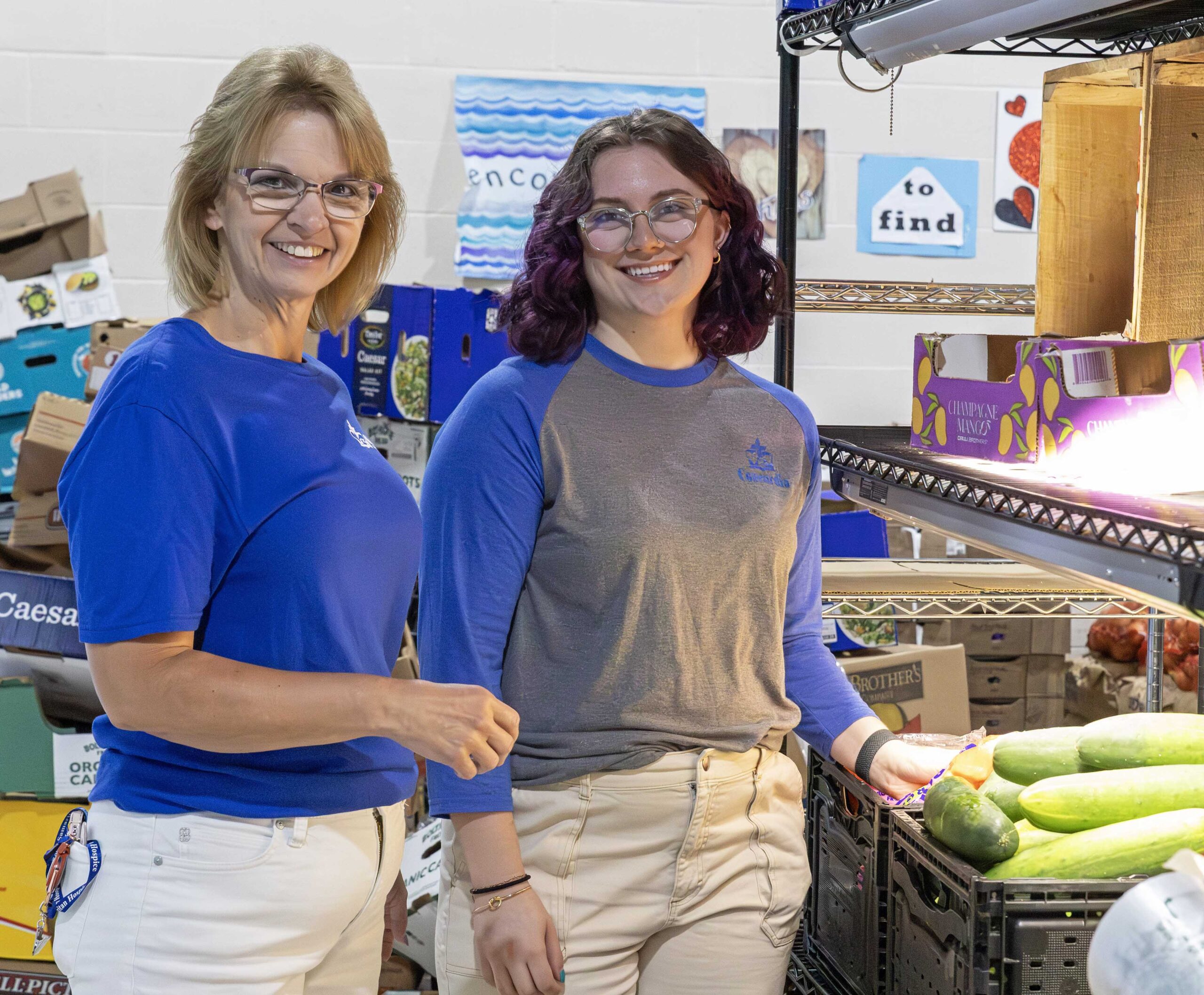 Two women smiling near fresh produce in a store.