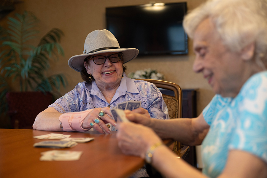 Two elderly women joyfully playing cards together.