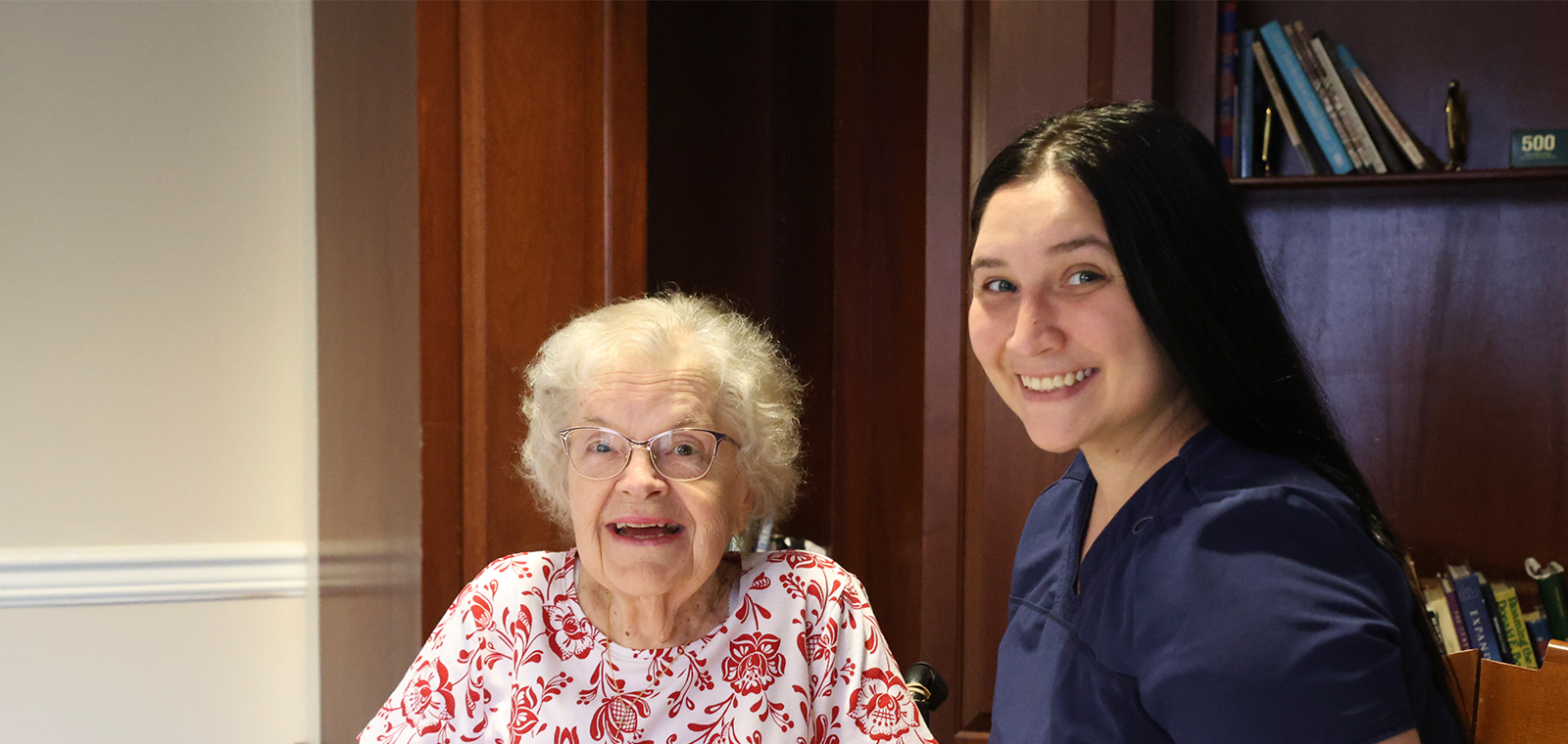 Smiling woman and elderly woman in a warm setting.