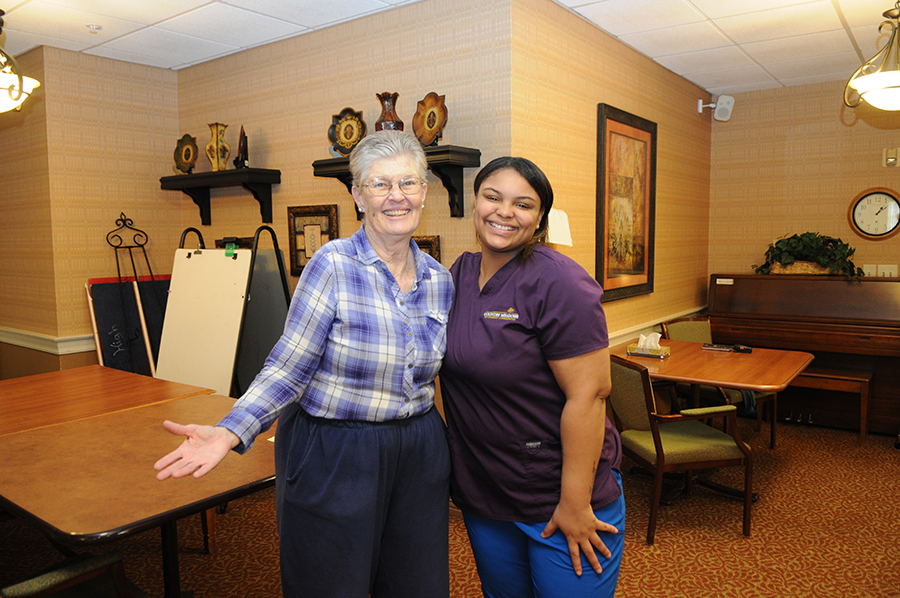 Smiling elderly woman and caregiver in a cozy setting.