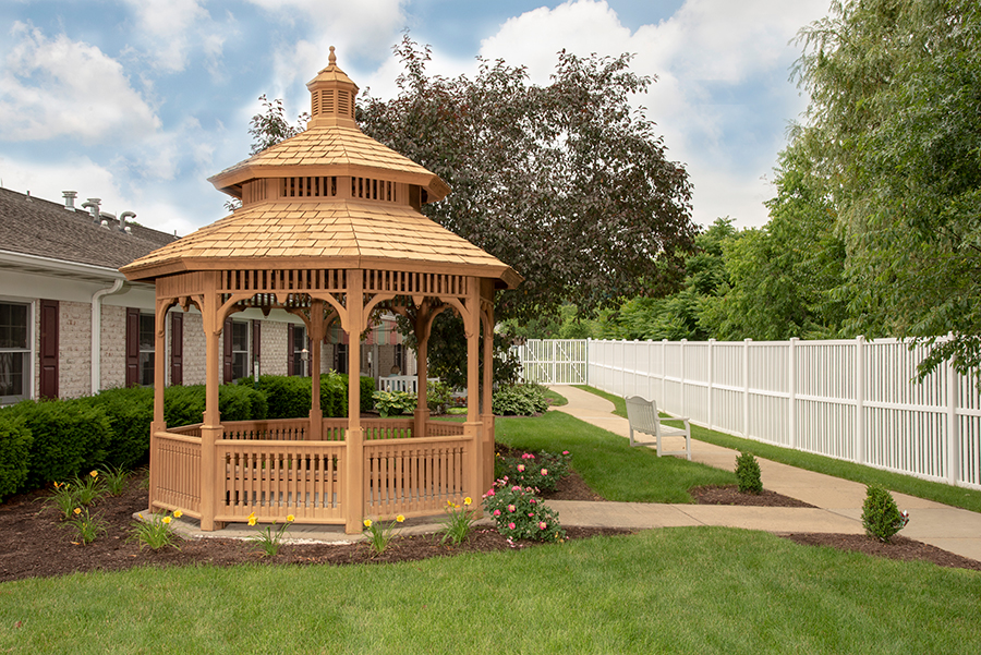 Wooden gazebo in a landscaped garden with a pathway.