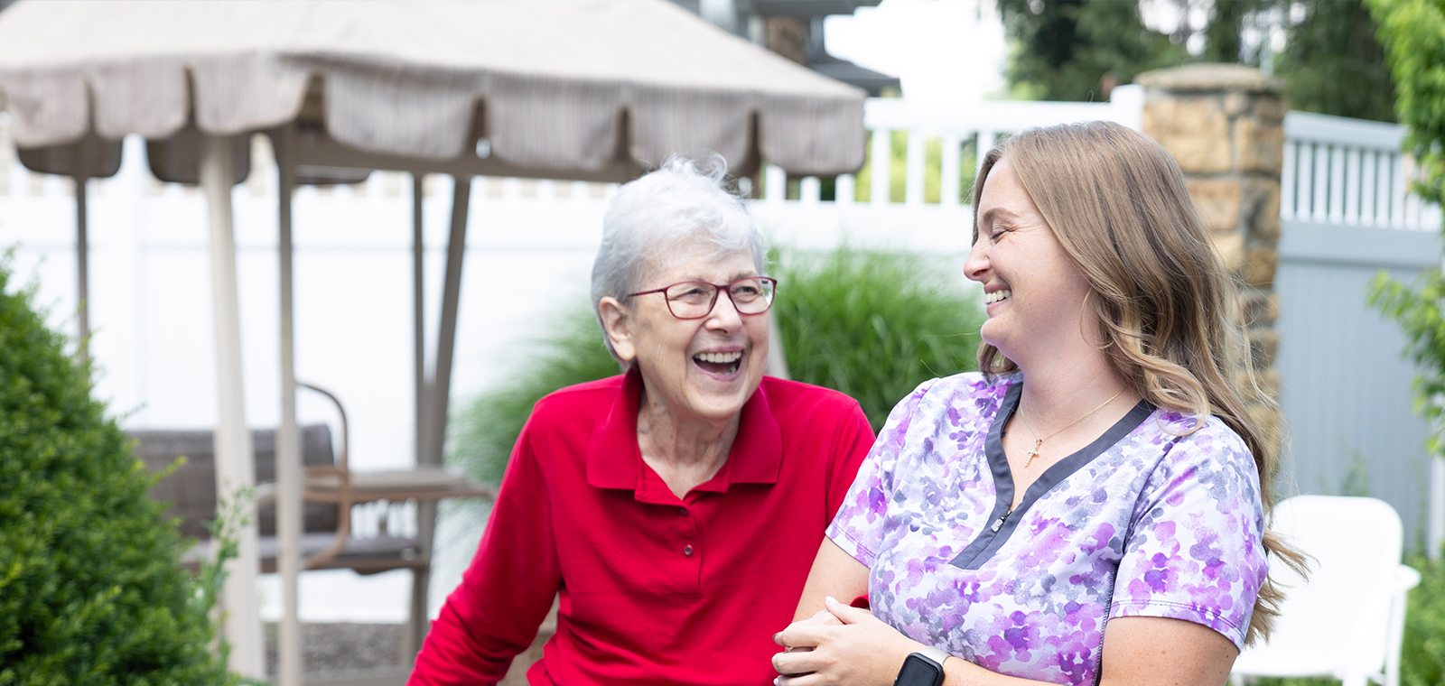 Two women laughing together outdoors, enjoying each other's company.