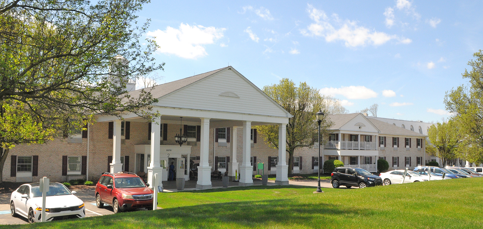 Residential building with parked cars and green grass.