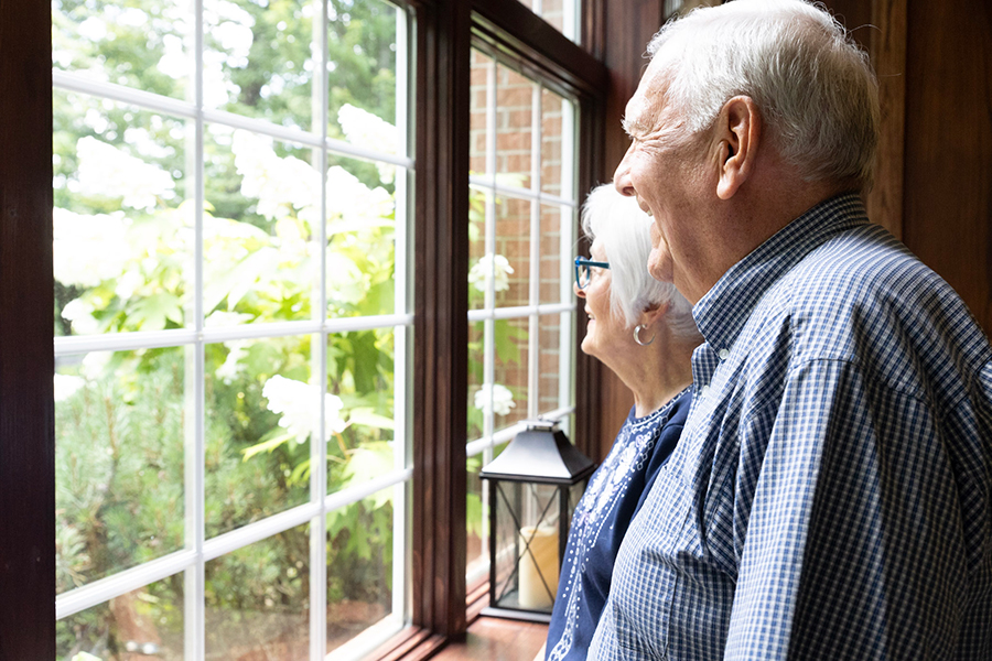 Elderly couple smiling while looking out the window.