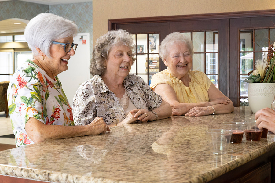 Three smiling women sitting at a bar counter.