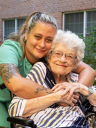 A young woman embraces an elderly woman, both smiling.