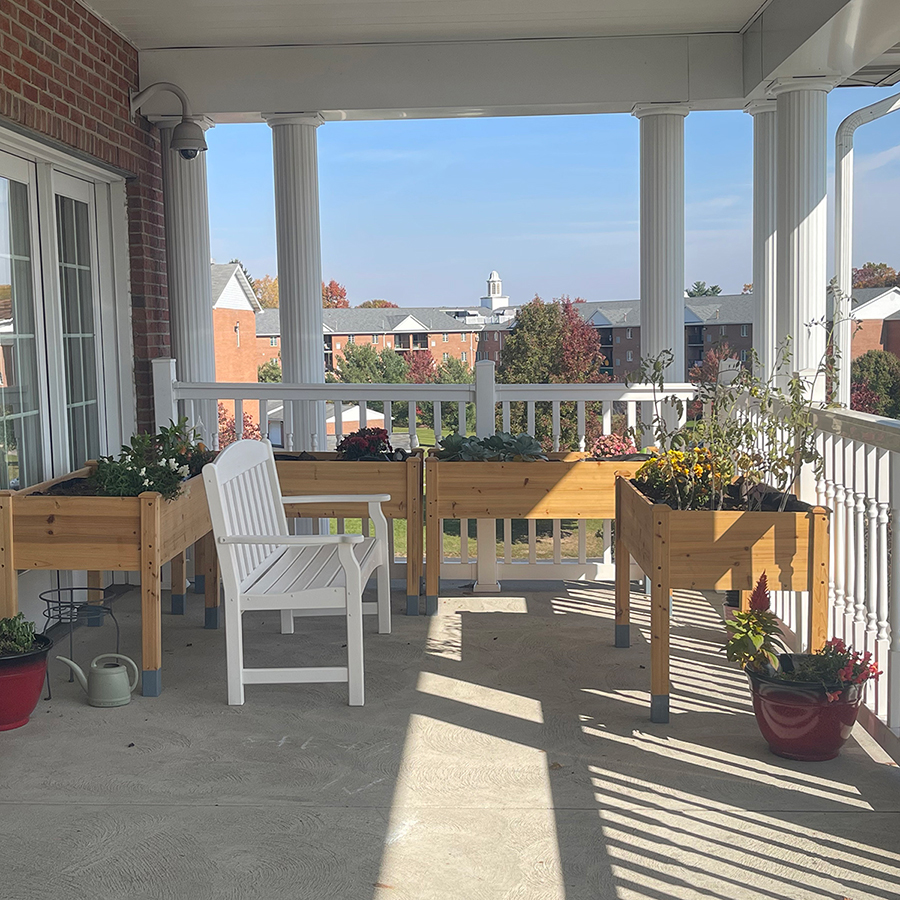Balcony with planters, chair, and vibrant autumn landscape.