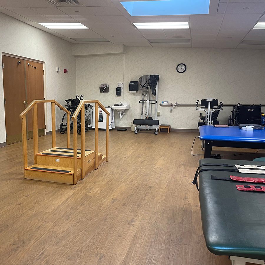 Physical therapy room with equipment and wooden steps.
