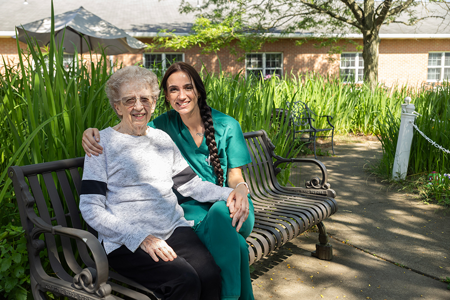 Two women smiling together in a garden setting.