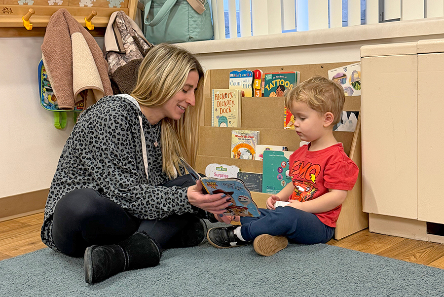 Woman reading to a young child on the floor.