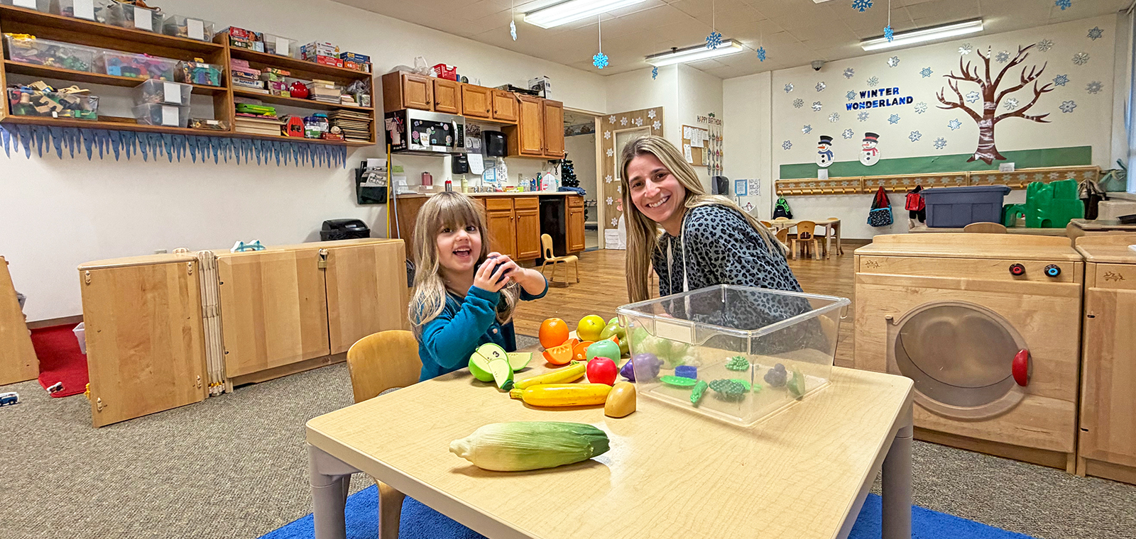 Child and adult playing with colorful toy fruits together.