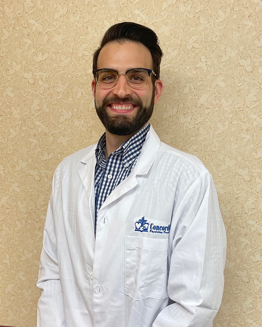 Smiling man in a lab coat against patterned background.