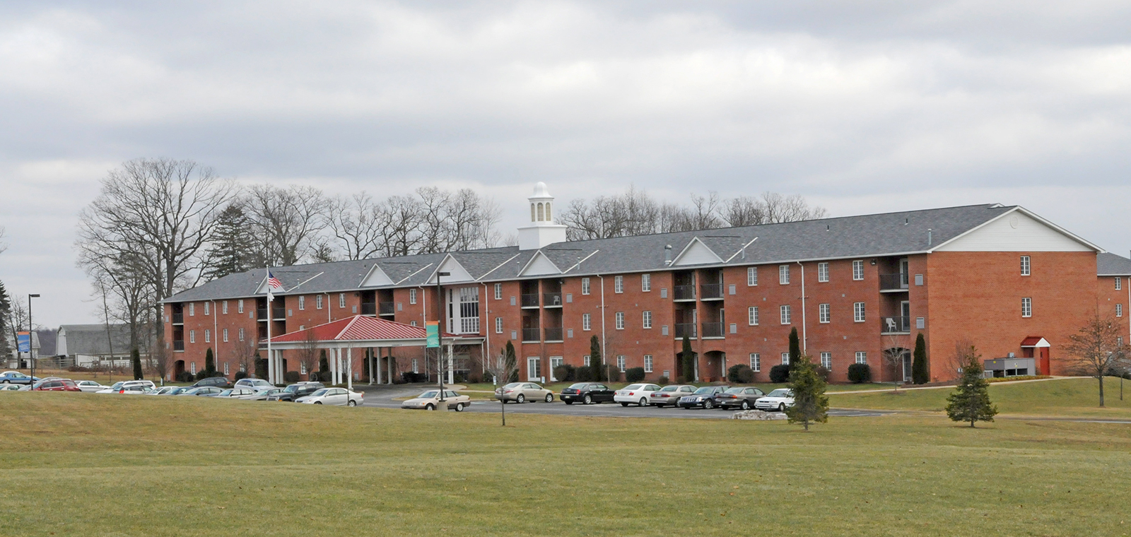 Brick building with parking lot and cloudy sky backdrop.