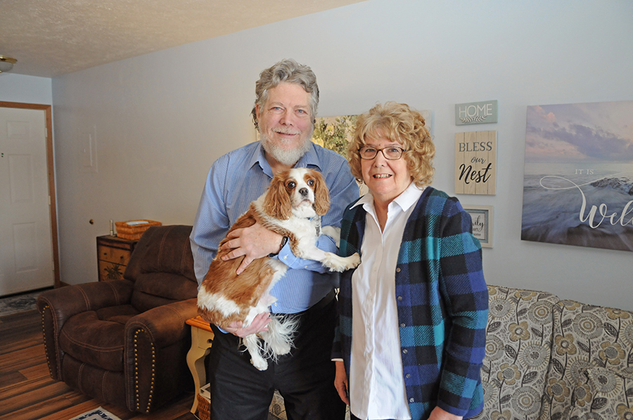 Couple holding a dog in a cozy living room.