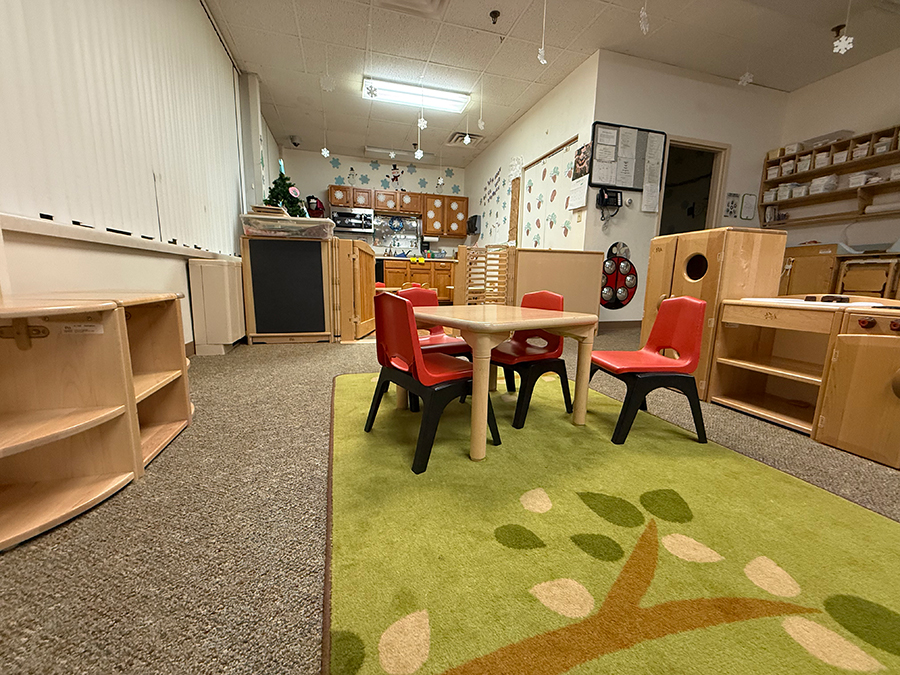 Classroom with wooden furniture and colorful rugs for children.