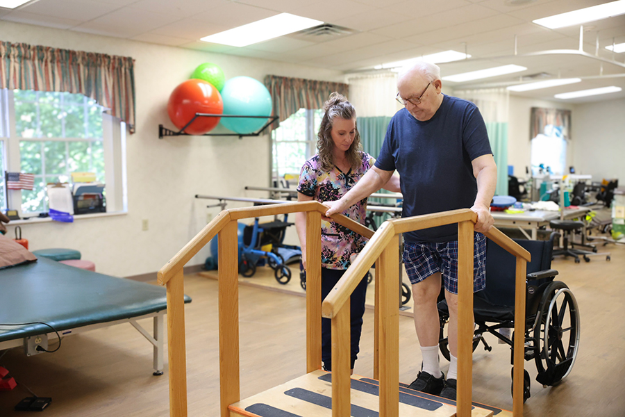 Therapist assists man with walking on rehabilitation stairs.