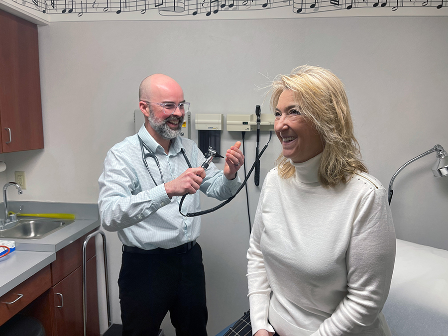 Doctor examining a smiling patient in a medical office.
