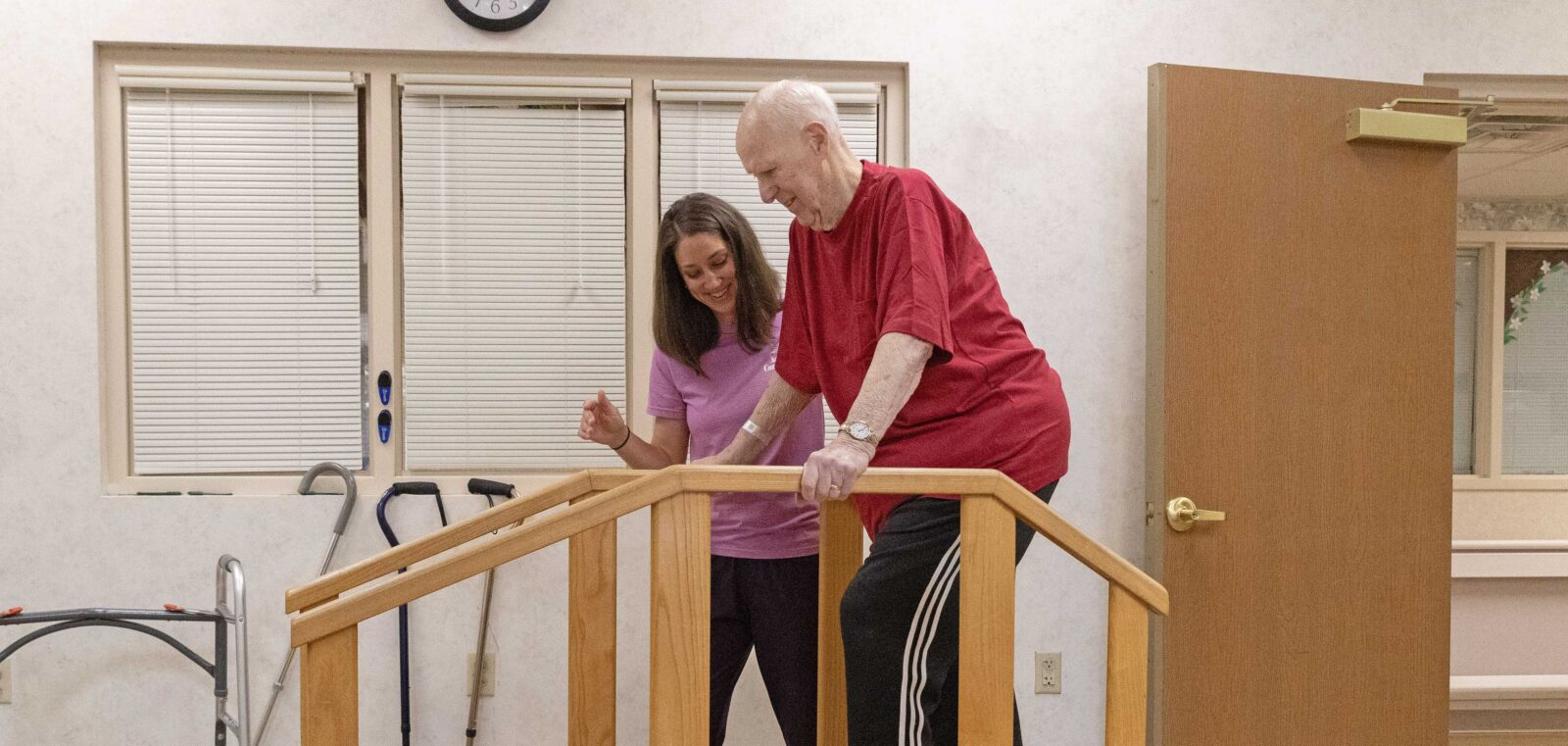 Man practicing walking with support from his therapist.