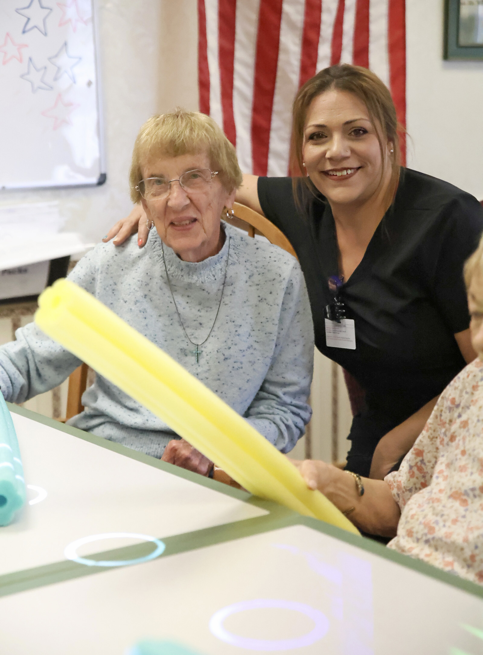 Women smiling together with colorful tubing in a care setting.