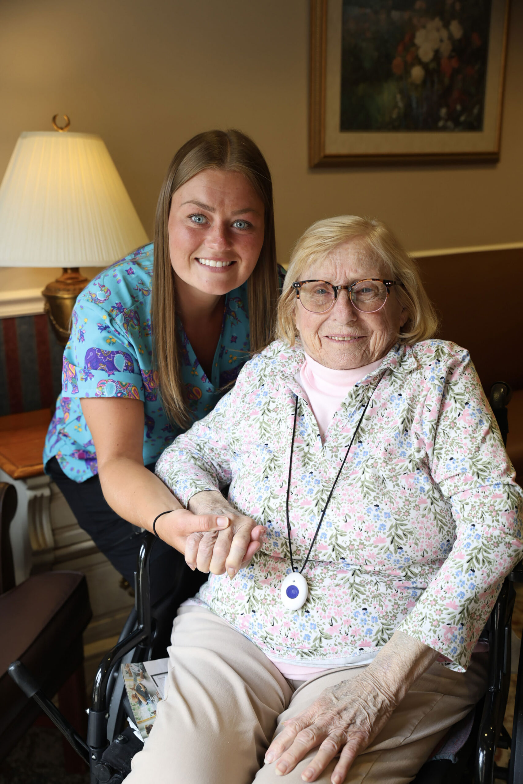 Smiling caregiver with elderly woman in wheelchair.