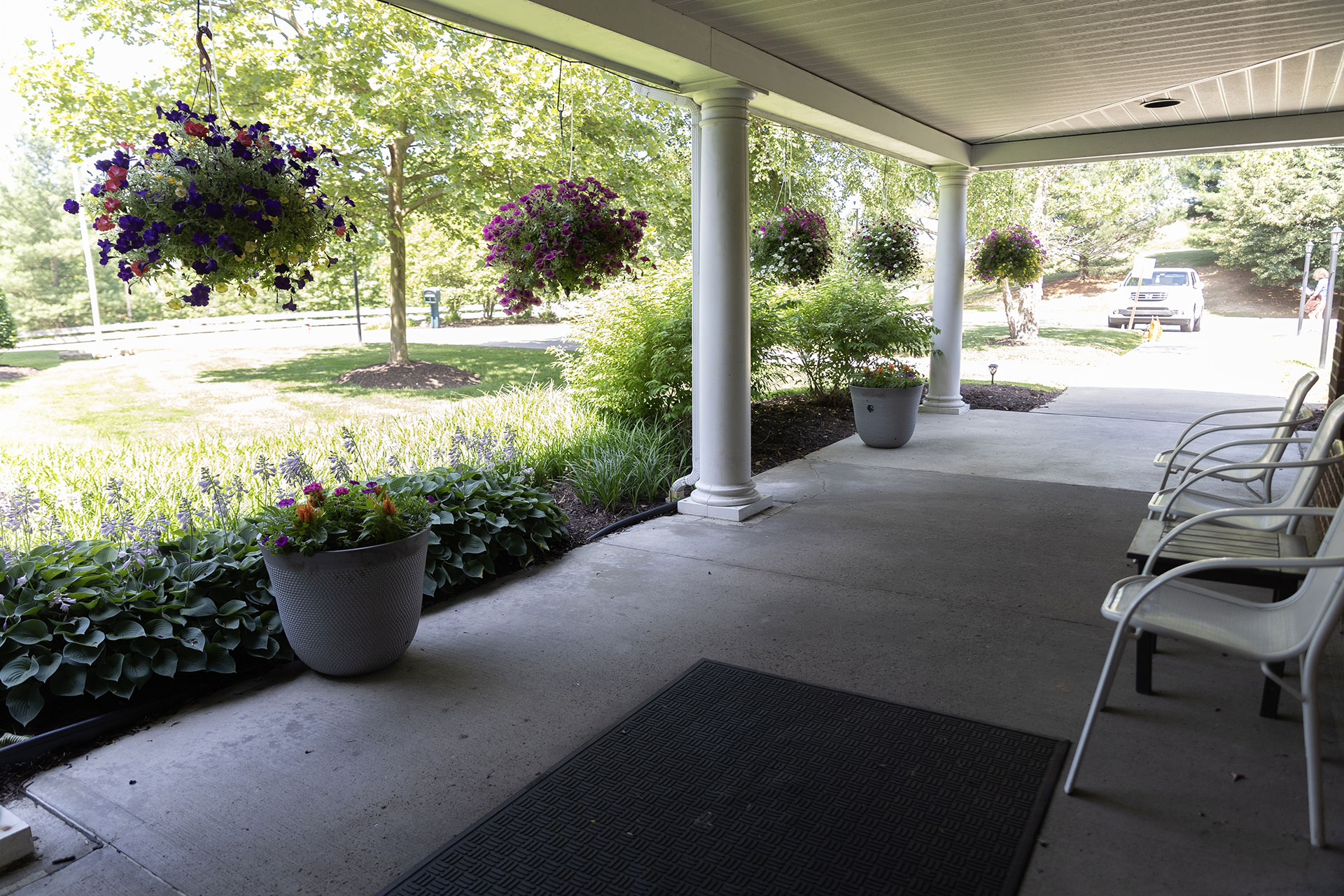 Welcoming porch with flowers, greenery, and seating area.