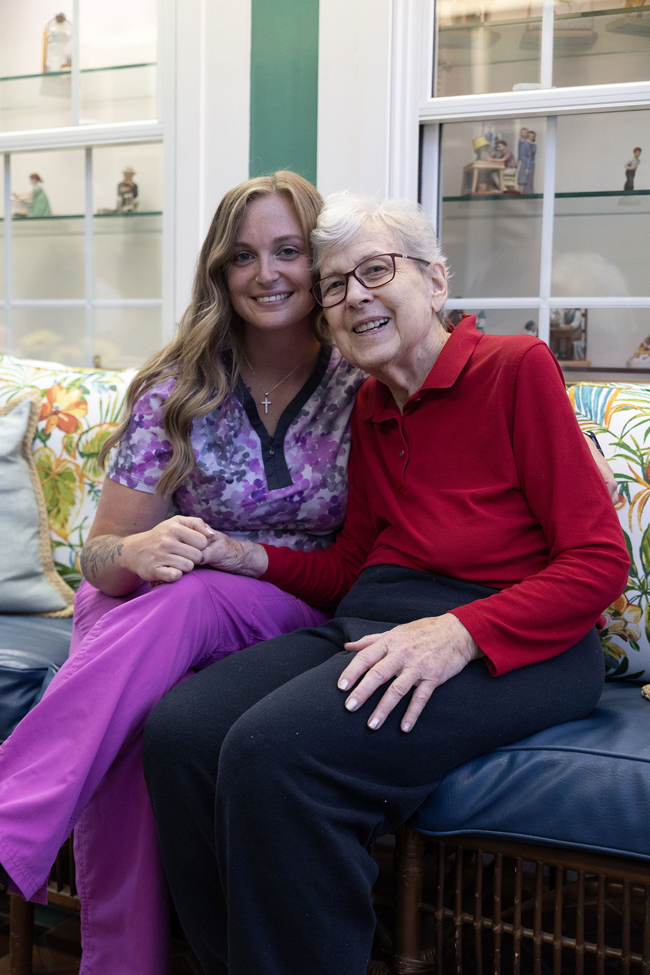 Two women smiling and posing together on a couch.