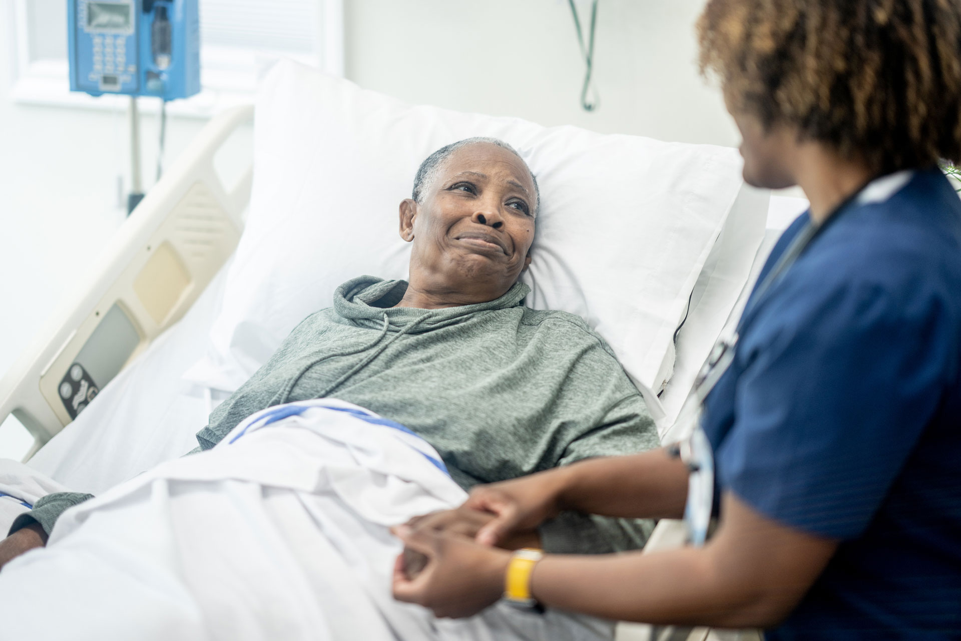 Patient and nurse share a comforting moment in a hospital.
