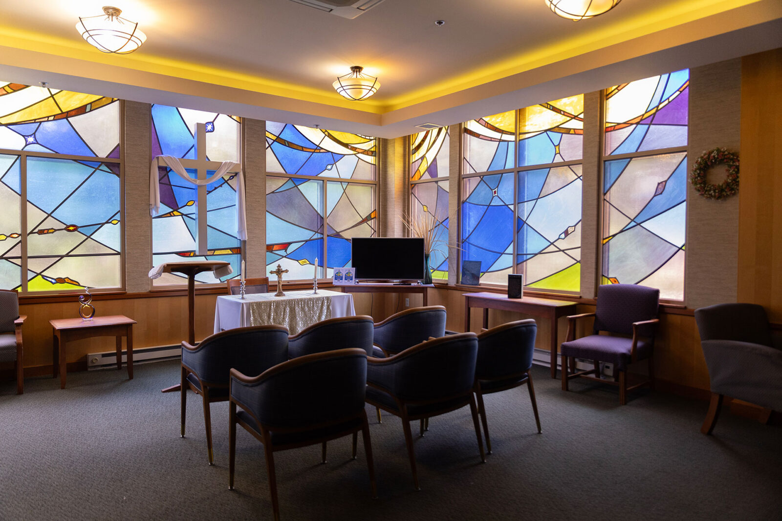 Chapel interior with stained glass windows and seating area.