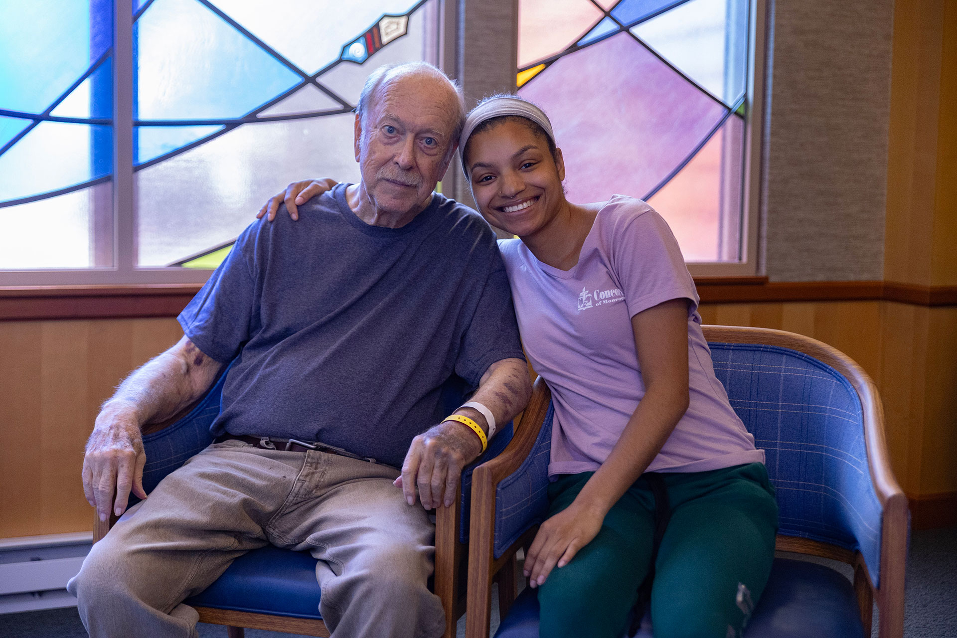 Elderly man and young woman sitting together, smiling.