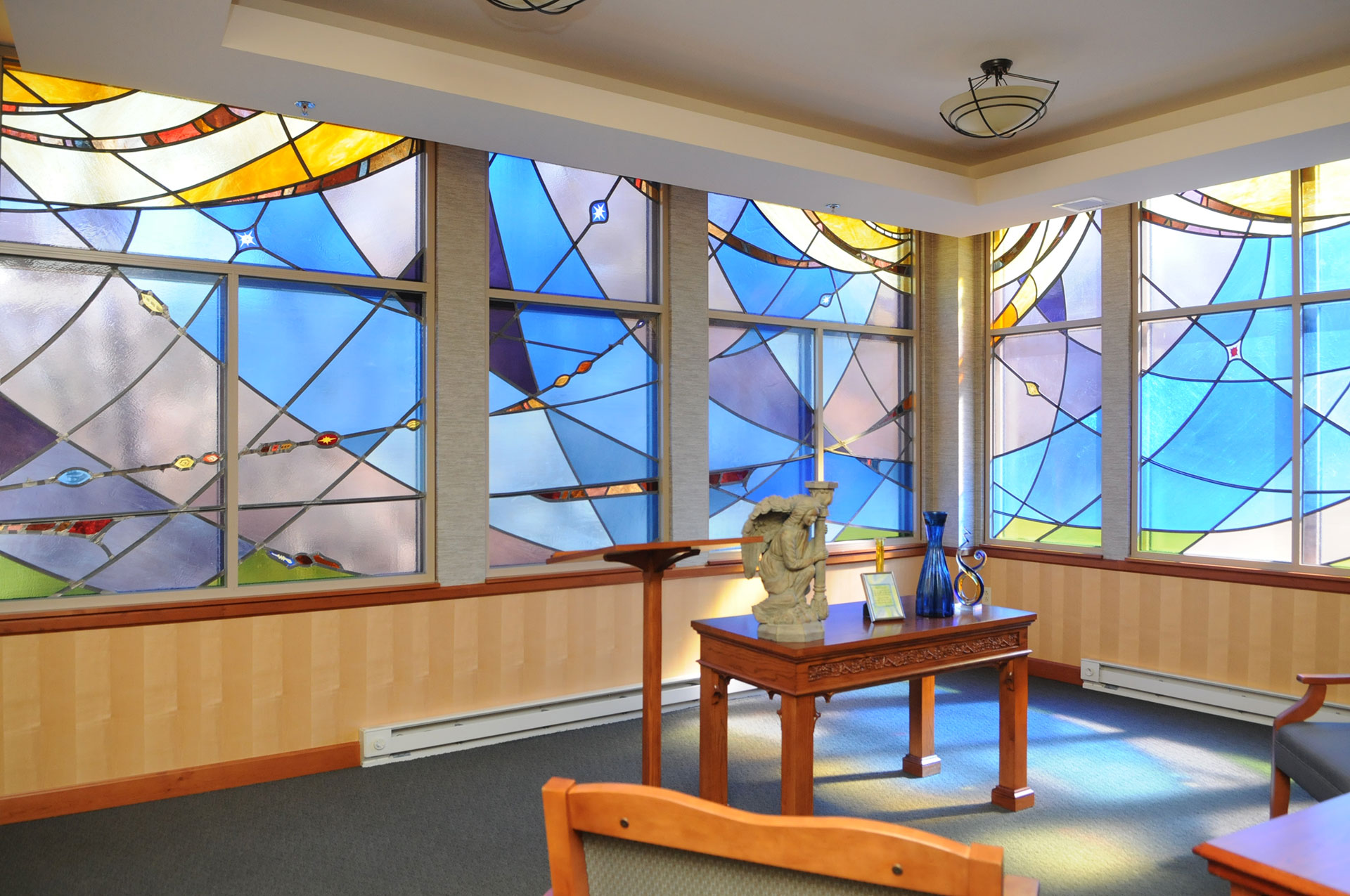 Colorful stained glass windows in a serene room interior.