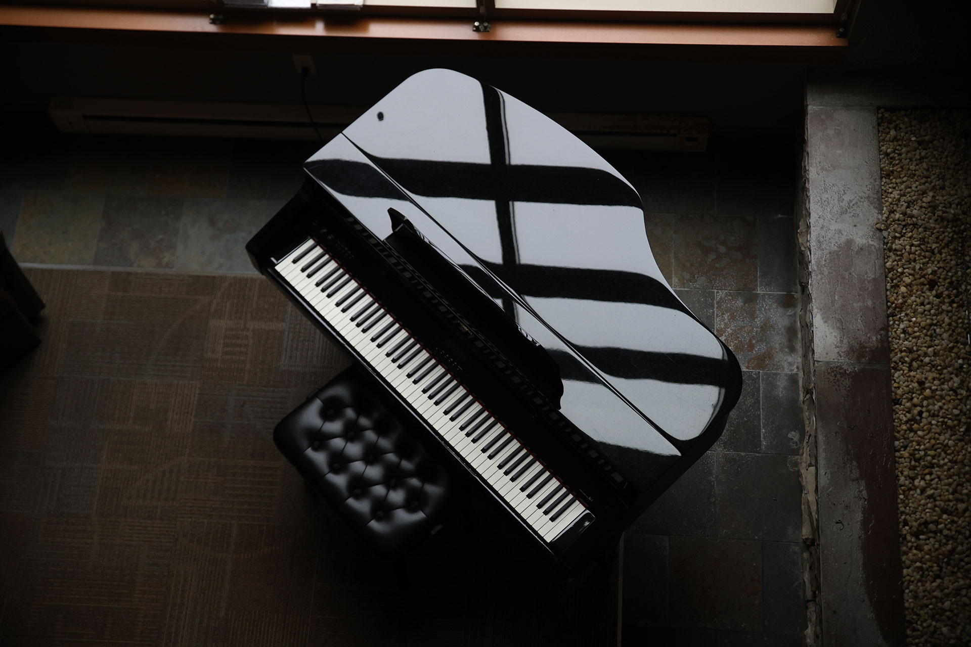 A grand piano with a reflective surface and black stool.