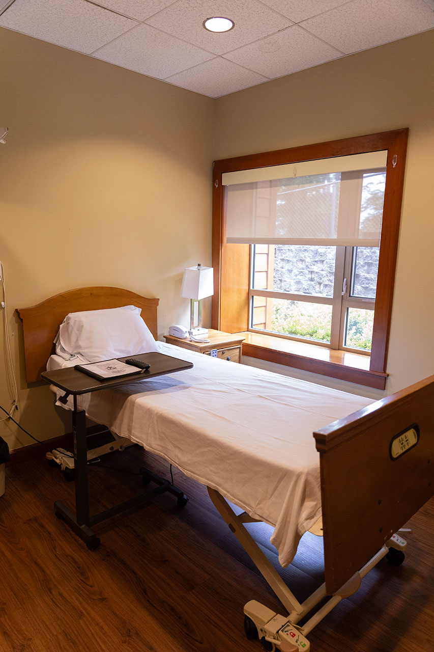 Empty hospital room with a bed and window.
