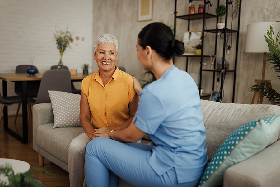 Caregiver interacting warmly with an older woman at home.