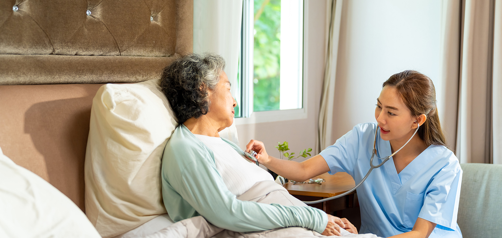 Nurse checking elderly patient's heartbeat in a cozy room.