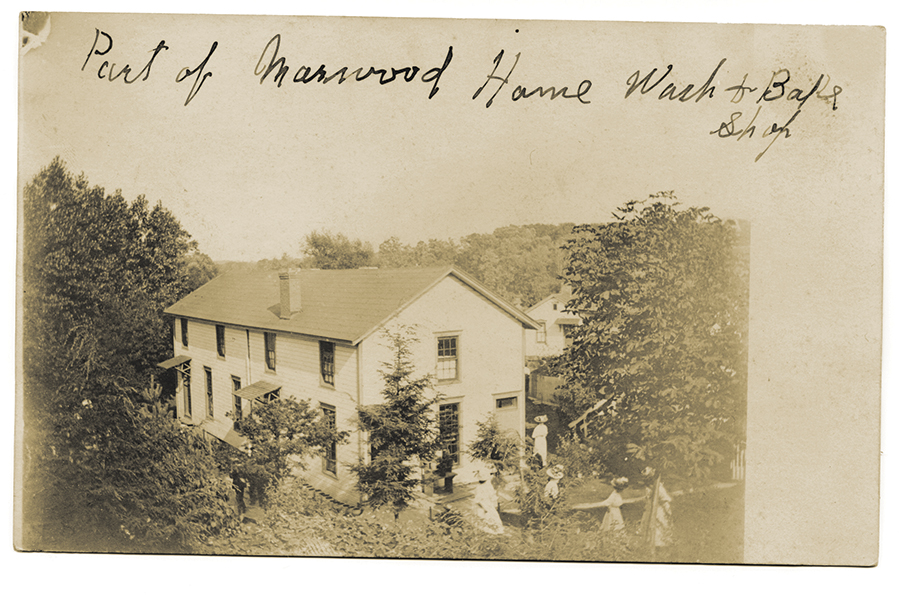 Historic photograph of a house with people outdoors.