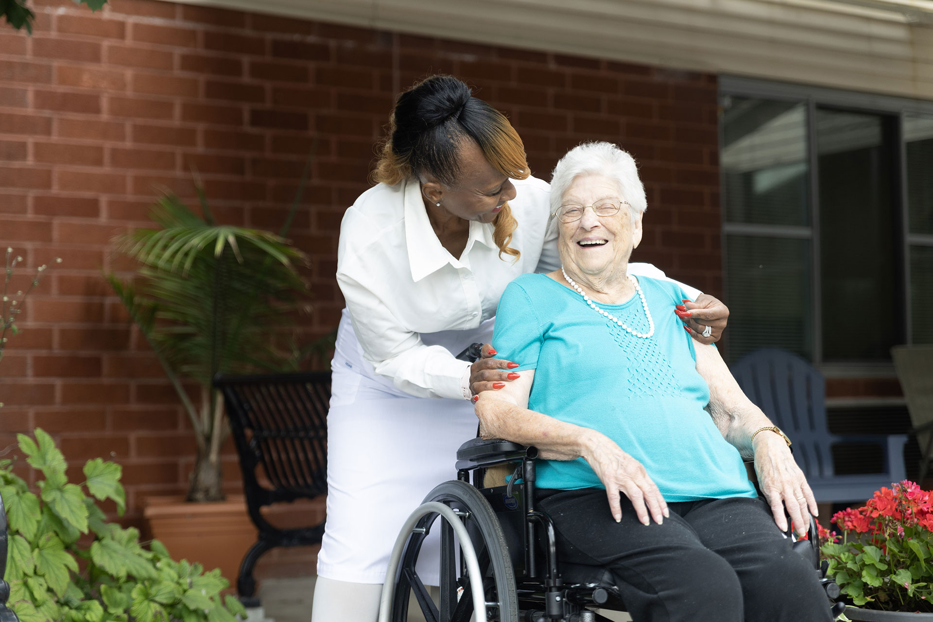 A caregiver and elderly woman share a joyful moment.