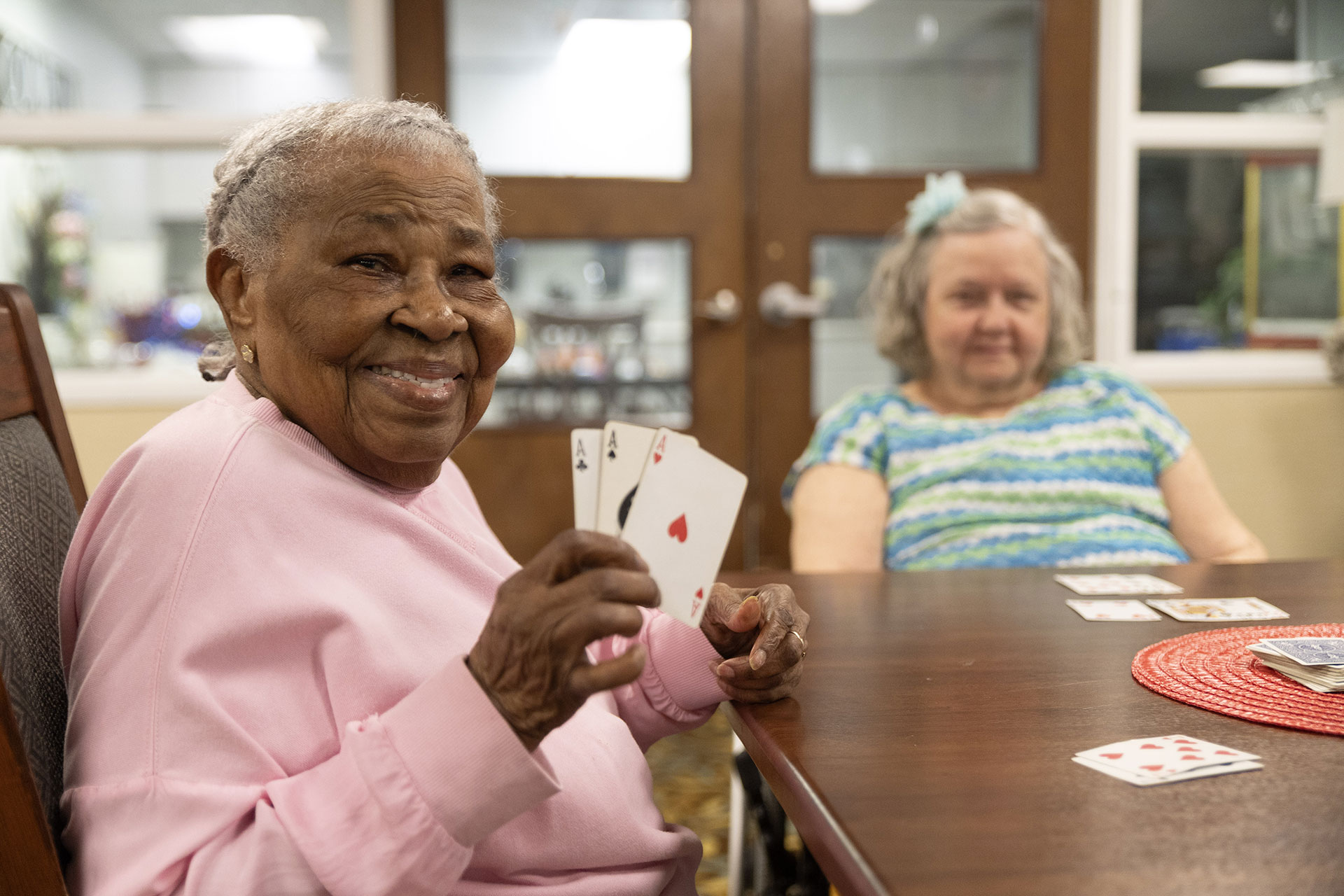 Two women playing cards, one smiling broadly.