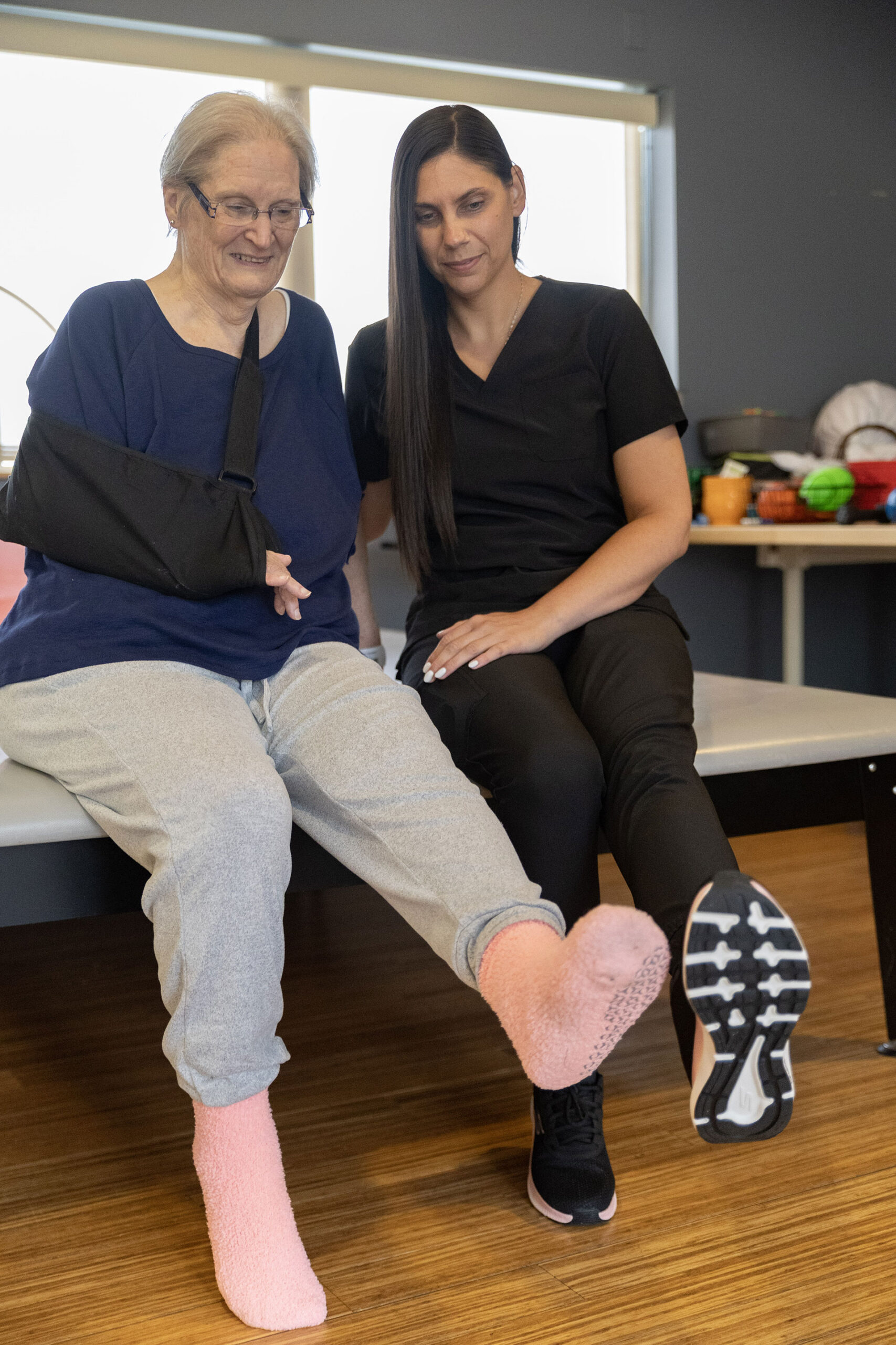 Two women sitting together, wearing contrasting socks.