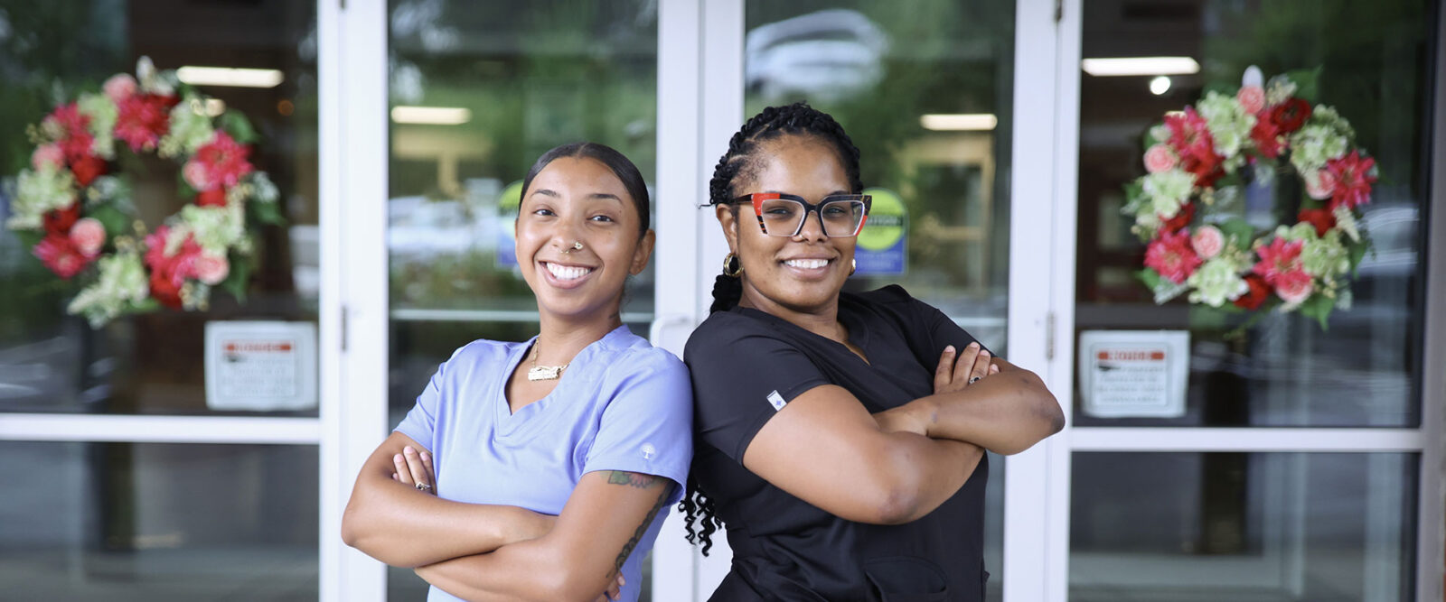 Two healthcare professionals posing confidently outside.