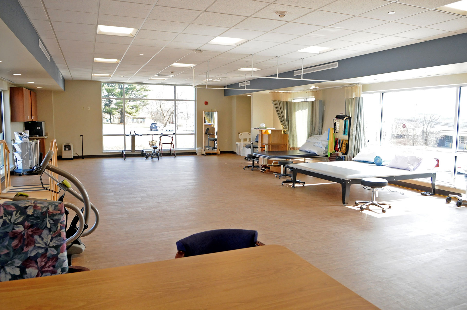 Spacious therapy room with equipment and large windows.