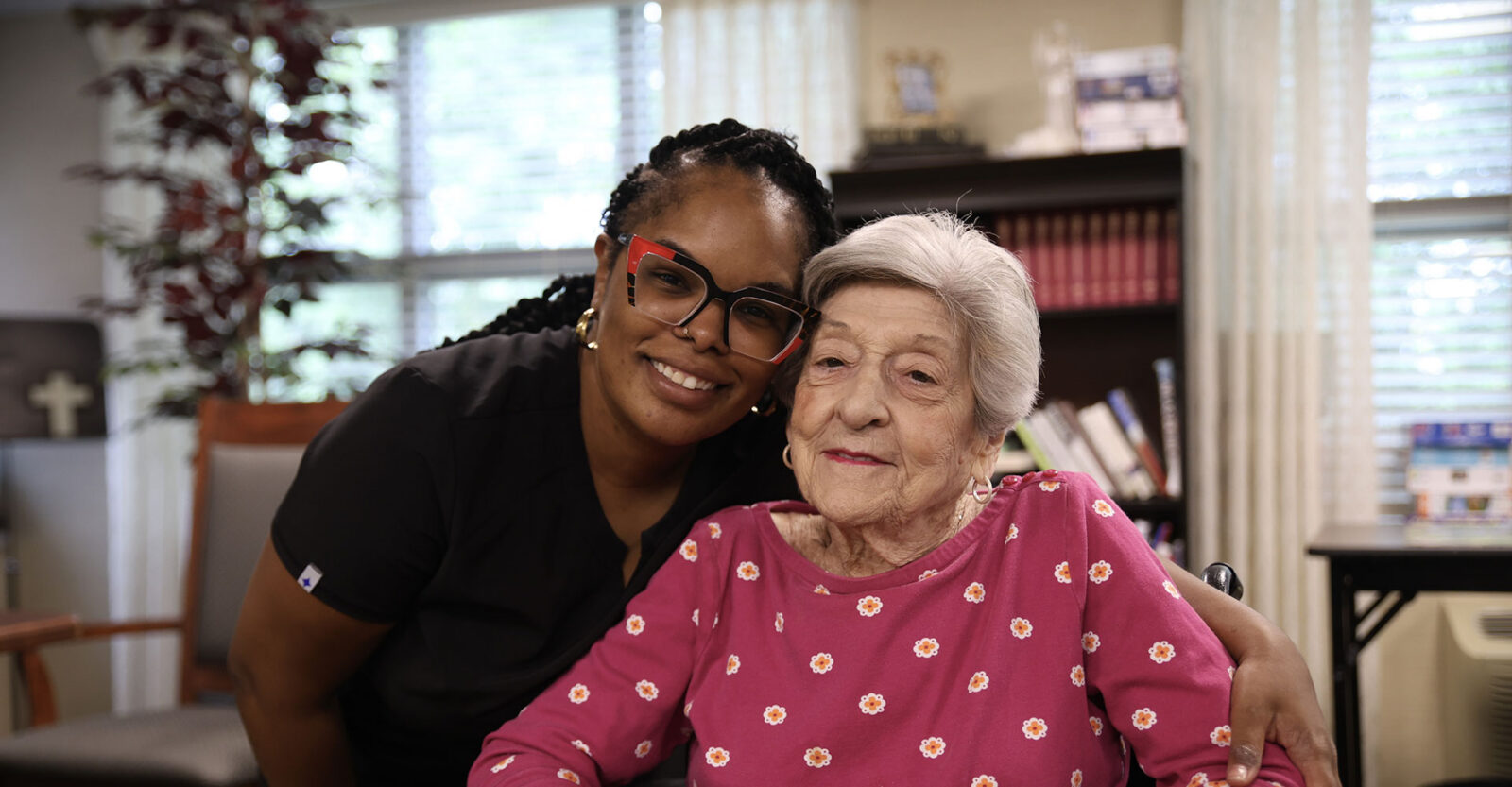 Smiling caregiver and elderly woman in a cozy setting.